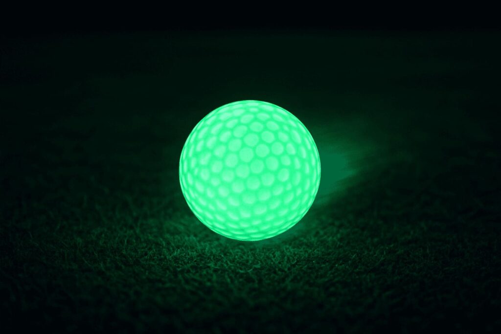 glowing green golf ball on turf at night